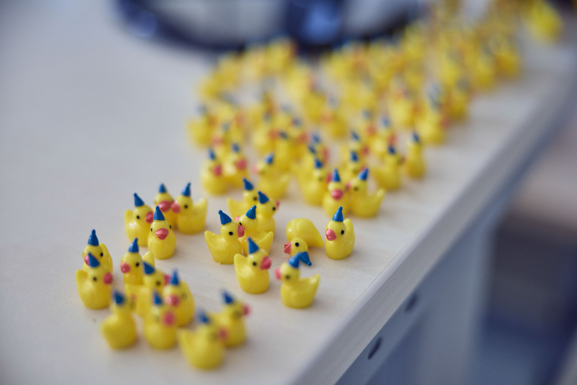 Eine Reihe von kleinen gelben Gummienten mit Partyhüten steht auf einem Tisch.